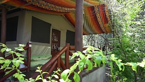 Un espacio al aire libre techado con barandal de madera, pared de concreto y vista a un paisaje natural.
