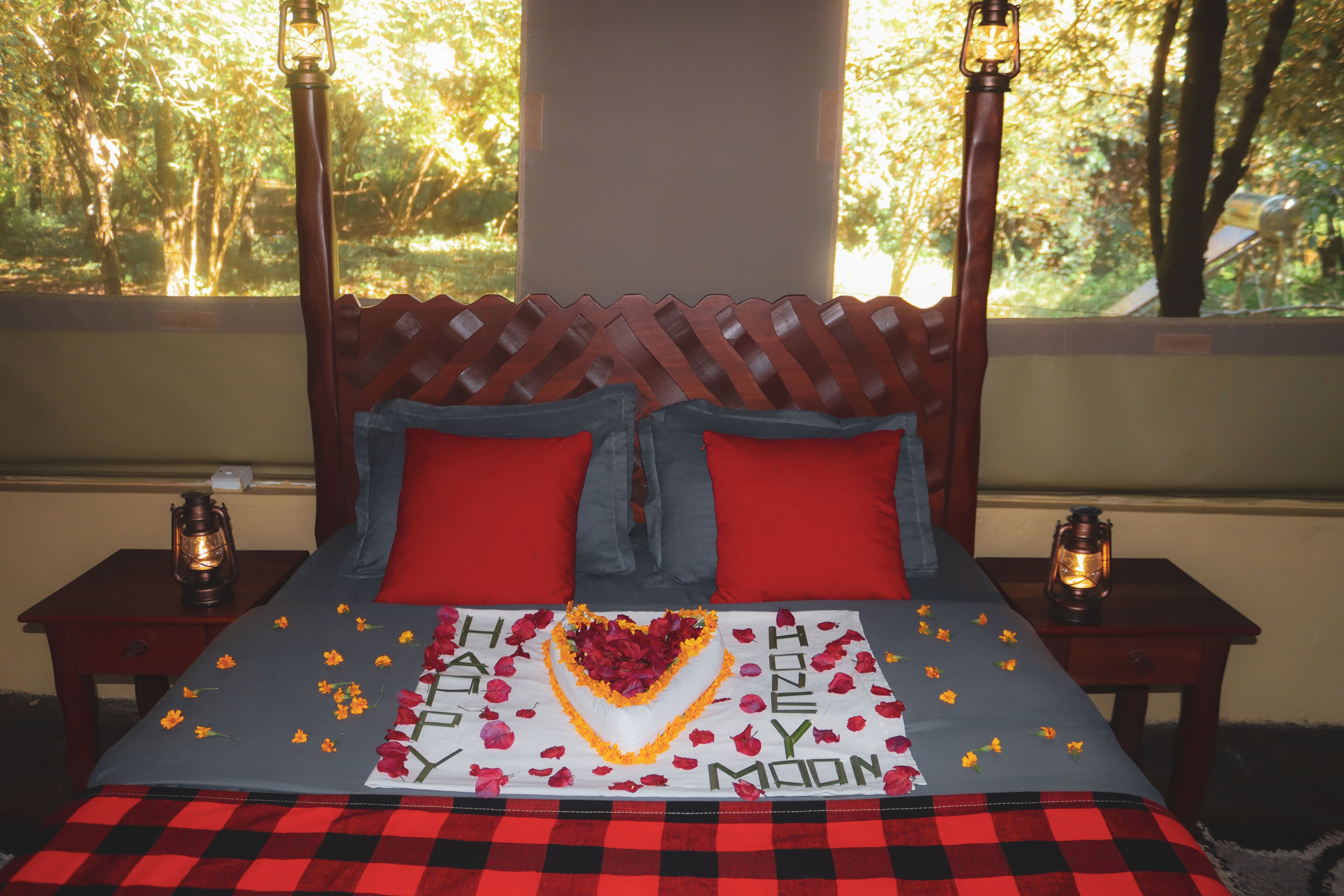 Un lit orné d’un motif en forme de cœur, avec des oreillers rouges et une couvre-lit sur laquelle est écrit « Bonne année ».