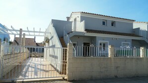 Un immeuble de deux étages doté d’un balcon et d’une entrée fermée par un portail.