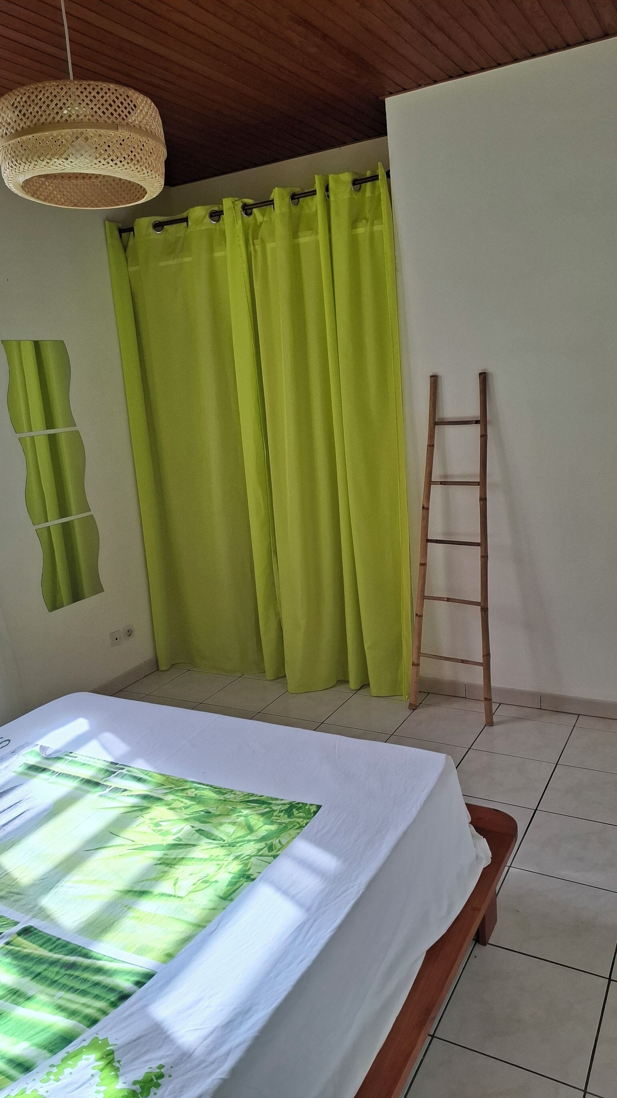 Una habitación con cama, una escalera y una cortina.