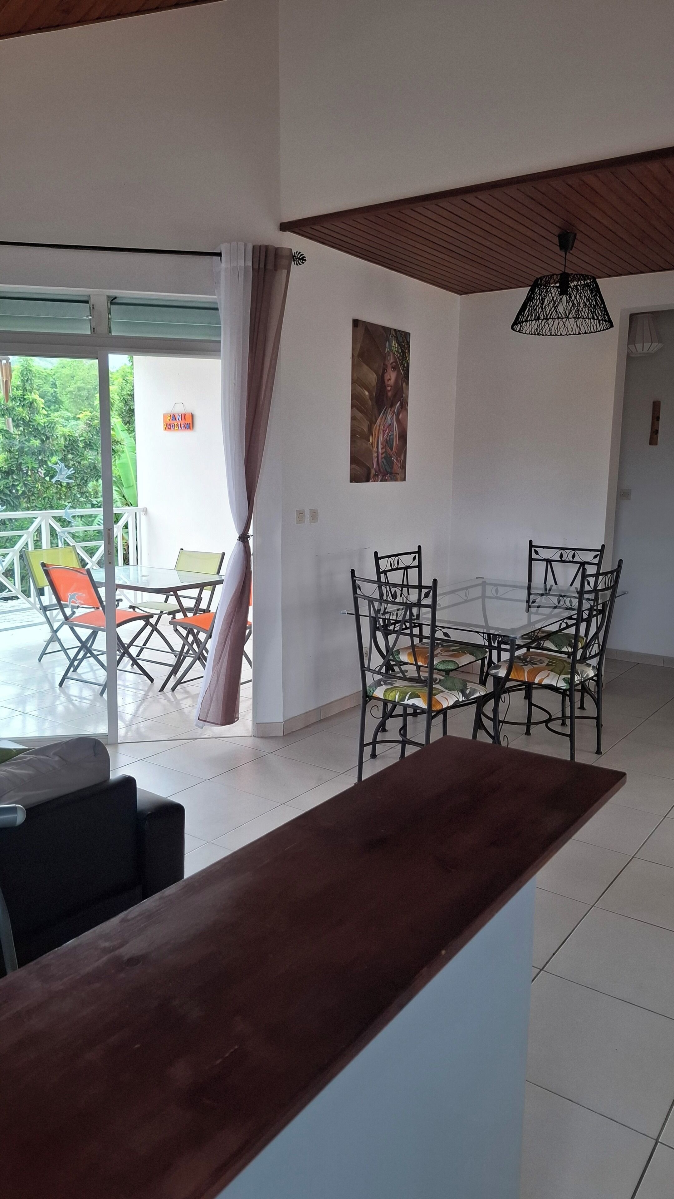 A dining area with a glass table and chairs, a wooden counter, and a view of the outdoors.