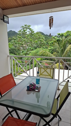 A glass-top table with chairs on a balcony, a bottle of water, and a small decorative item.