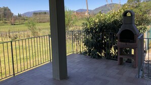 A covered patio with a brick floor, a metal fence, and a stone oven. - Bright country villa, with veranda, pool, garden, near Florence (Buggiano)