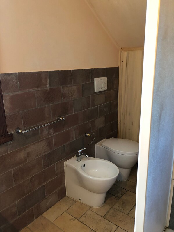 Un baño pequeño con inodoro, bidé y un perchero para toallas.