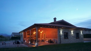 A stone building with a covered patio and outdoor seating area. - Albergue La Cala (Ribamontan al Mar)