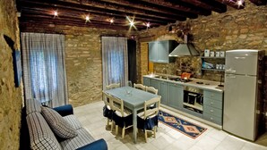 A compact kitchen with a dining area, stone walls, and a modern refrigerator. - Apartment in a nineteenth-century house                                        (Cervarese Santa Croce)