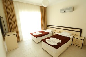 Une chambre d’hôtel avec deux lits, un petit bureau, une table de chevet et un appareil de climatisation.