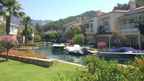 Un canal où naviguent des bateaux, bordé d’une végétation luxuriante et de bâtiments traditionnels dotés de balcons.