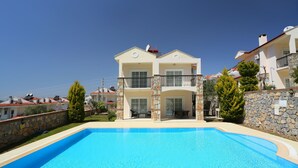 Une maison à deux étages avec une piscine à l’avant.