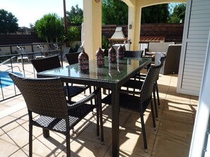 An outdoor patio with a glass-top table, wicker chairs, and decorative vases. - Large detached family Villa with private pool and beautiful gardens, full a/c. (Peyia)
