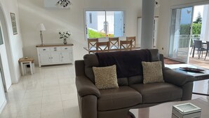 Ein Wohnzimmer mit einem braunen Sofa, einem Glastisch und einem weißen Schrank.