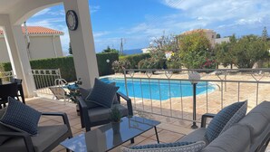 Eine Terrasse mit Gartenmöbeln, einem Pool und Blick auf das Meer.