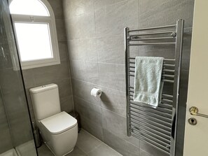 A bathroom with a toilet, a towel rack with a towel, and a toilet paper holder. - Large detached family Villa with private pool and beautiful gardens, full a/c. (Peyia)