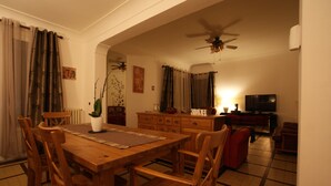 A dining area with a wooden table and chairs, a ceiling fan, and a TV in the background. - Villa with private pool in Carcassonne town, quiet area with castle views (Carcassonne)