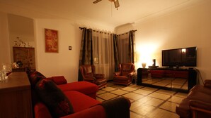A living room with a red sofa, two leather armchairs, a television, and a wooden coffee table. - Villa with private pool in Carcassonne town, quiet area with castle views (Carcassonne)