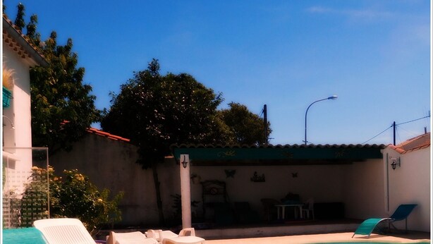A swimming pool with two sections, surrounded by lounge chairs and a covered seating area. - Villa with private pool in Carcassonne town, quiet area with castle views (Carcassonne)