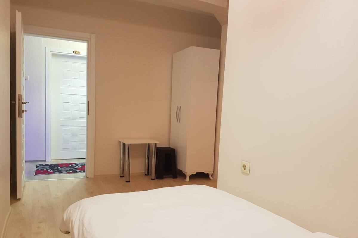 Ein Schlafzimmer mit einem Bett, einem Kleiderschrank, einem kleinen Tisch und einer Tür zu einem anderen Raum.