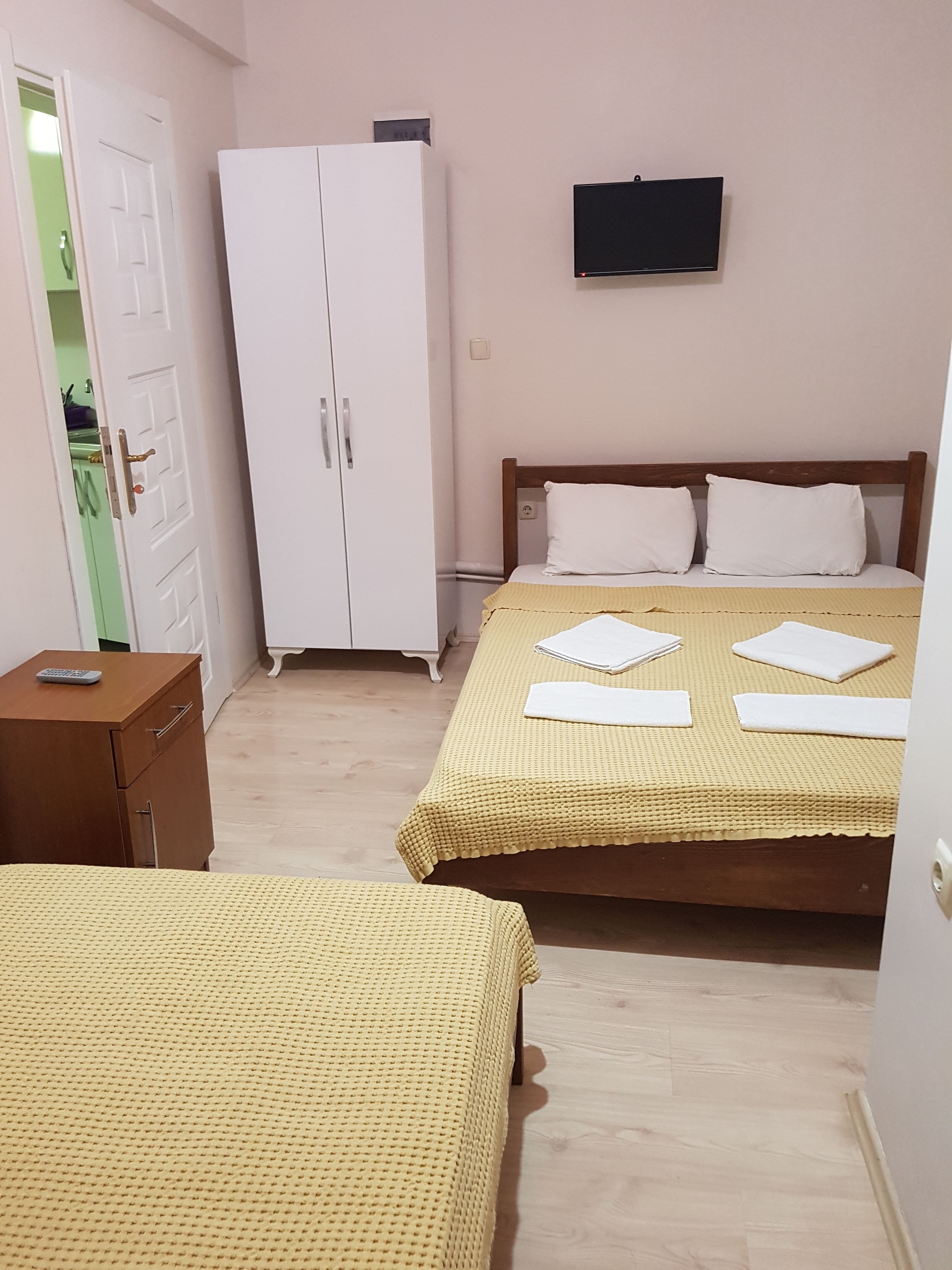 Un dormitorio con dos camas, un armario, un televisor y un escritorio pequeño con un control remoto.