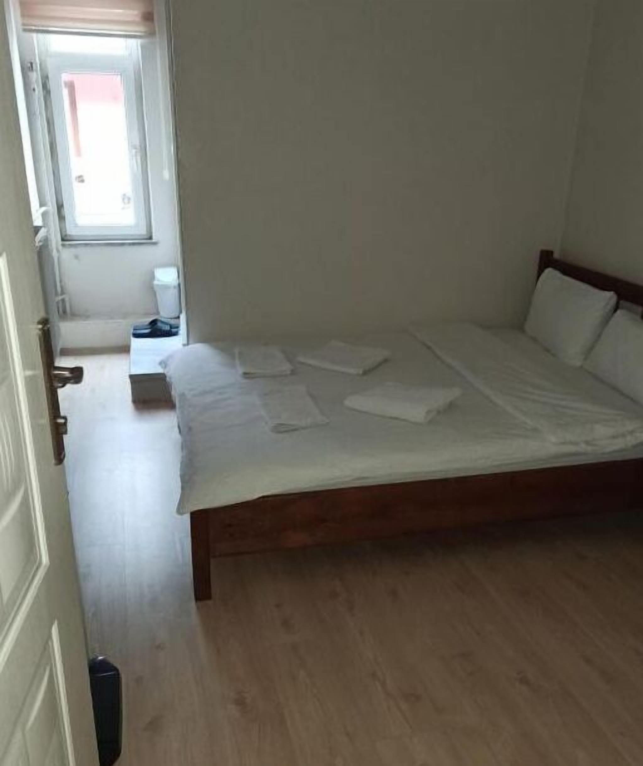 A bedroom with a wooden bed, a small bedside table, and a window.