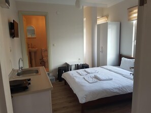 Una habitación de hotel con cama, lavamanos, espejo, armario y un taburete pequeño.