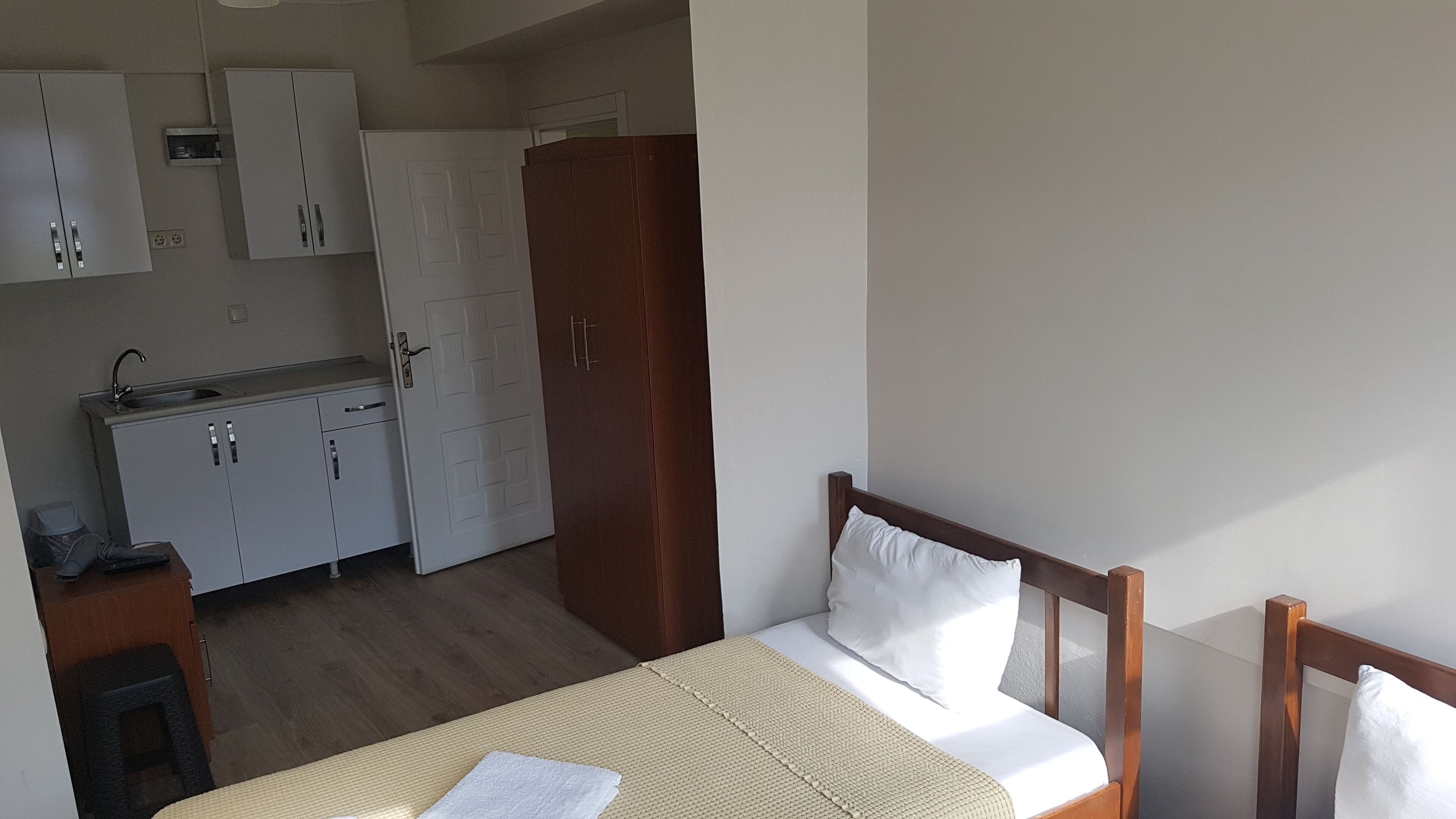 Habitació senzilla amb llit, escriptori petit, zona de cuina i armari.