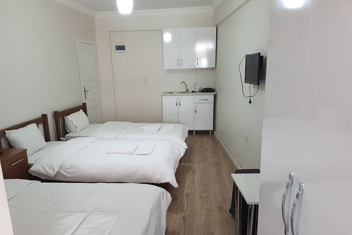 Ein Hotelzimmer mit zwei Betten, einer kleinen Küchenzeile, einem Spiegel und einem Fernseher.