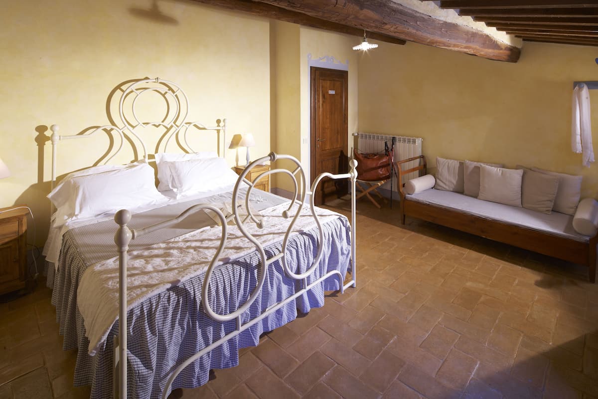 A bedroom with a bed, a bench, and a wooden door.