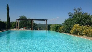 A clear blue pool with a wooden pergola and benches, surrounded by lush greenery and trees. - Tregole (Castellina in Chianti)