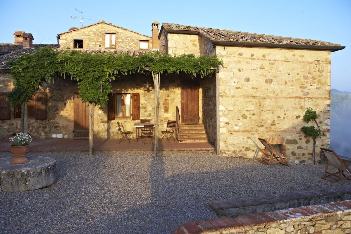 A stone building with a covered patio, outdoor seating, and a small garden area.