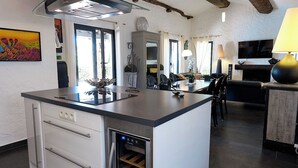A modern kitchen with a central island, built-in wine cooler, and a ceiling fan. - 400m from the sea, Villa with splendid sea view, heated infinity pool (Fréjus)