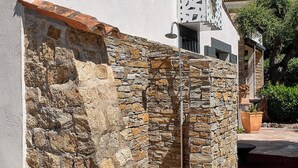 A building with a stone wall, a white facade, and a decorative lattice structure. - 400m from the sea, Villa with splendid sea view, heated infinity pool (Fréjus)