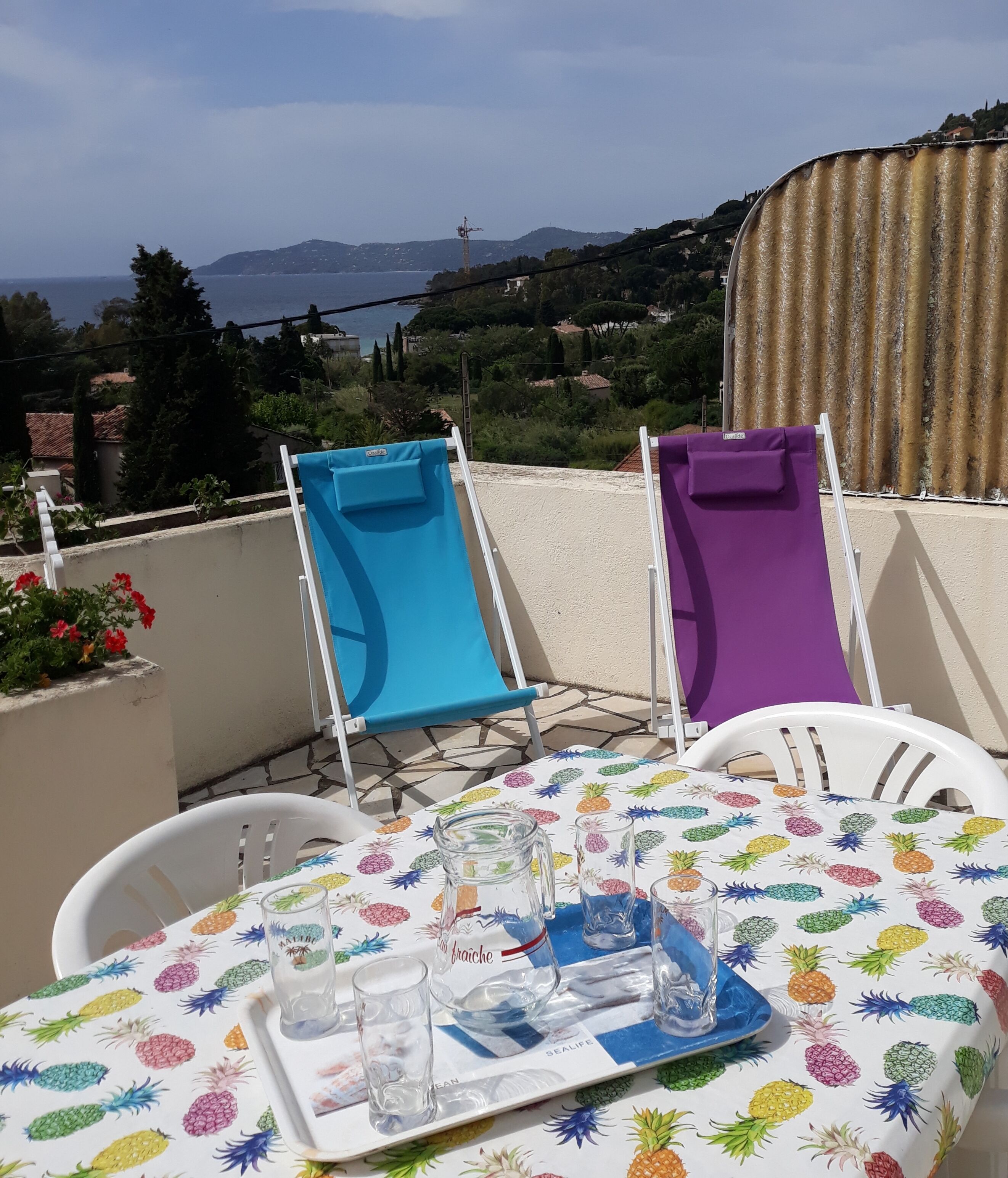 A table set with chairs and a tray, overlooking a scenic view of the sea and hills.
