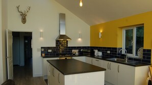 A modern kitchen with a central island, black and white cabinetry, a stainless steel range hood, and a decorative deer head on the wall.