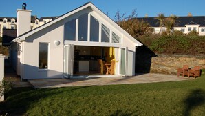 A modern house with a large glass door leading to a patio area with outdoor furniture.