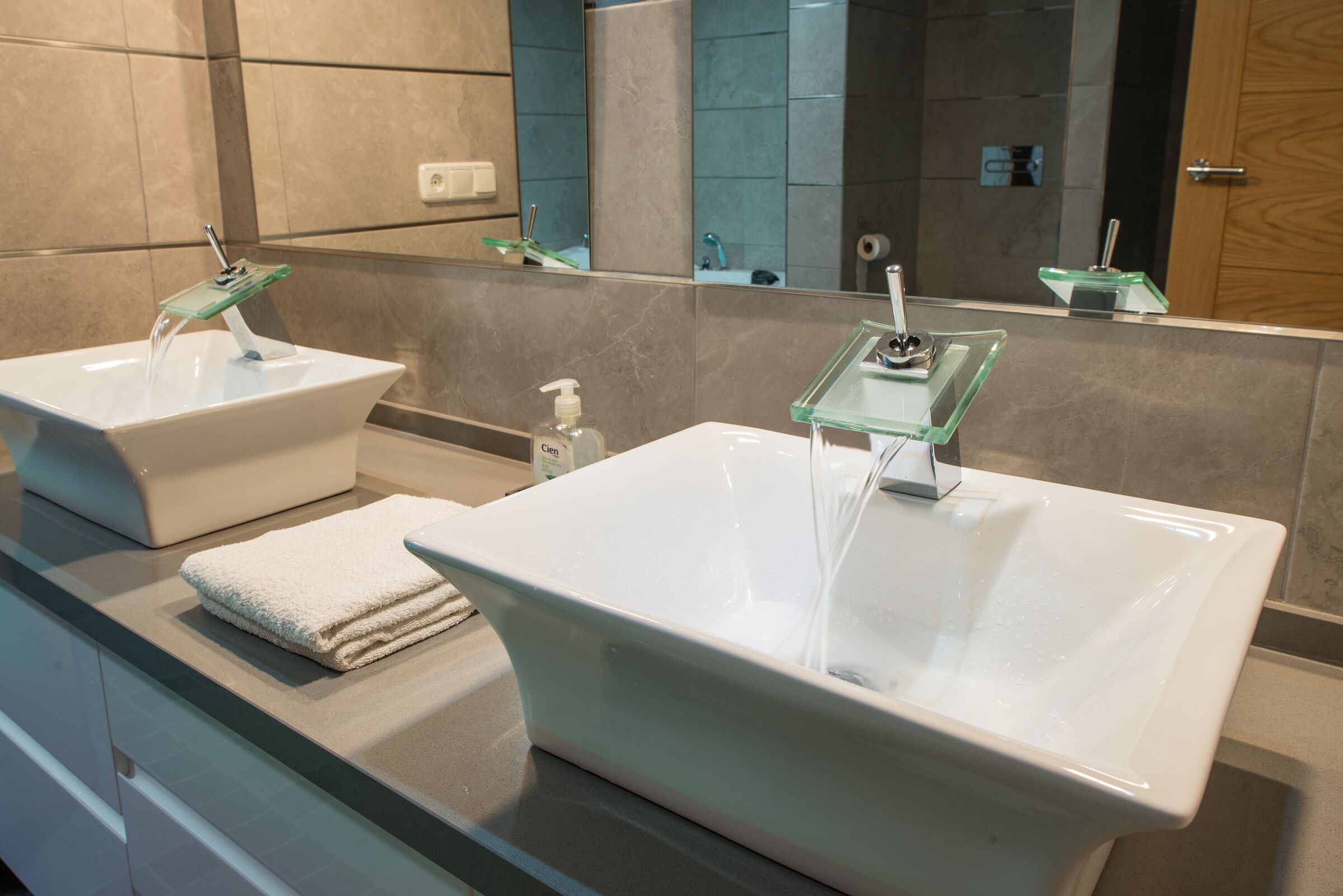 Une salle de bain avec deux lavabos, un miroir et une serviette posée sur le comptoir.