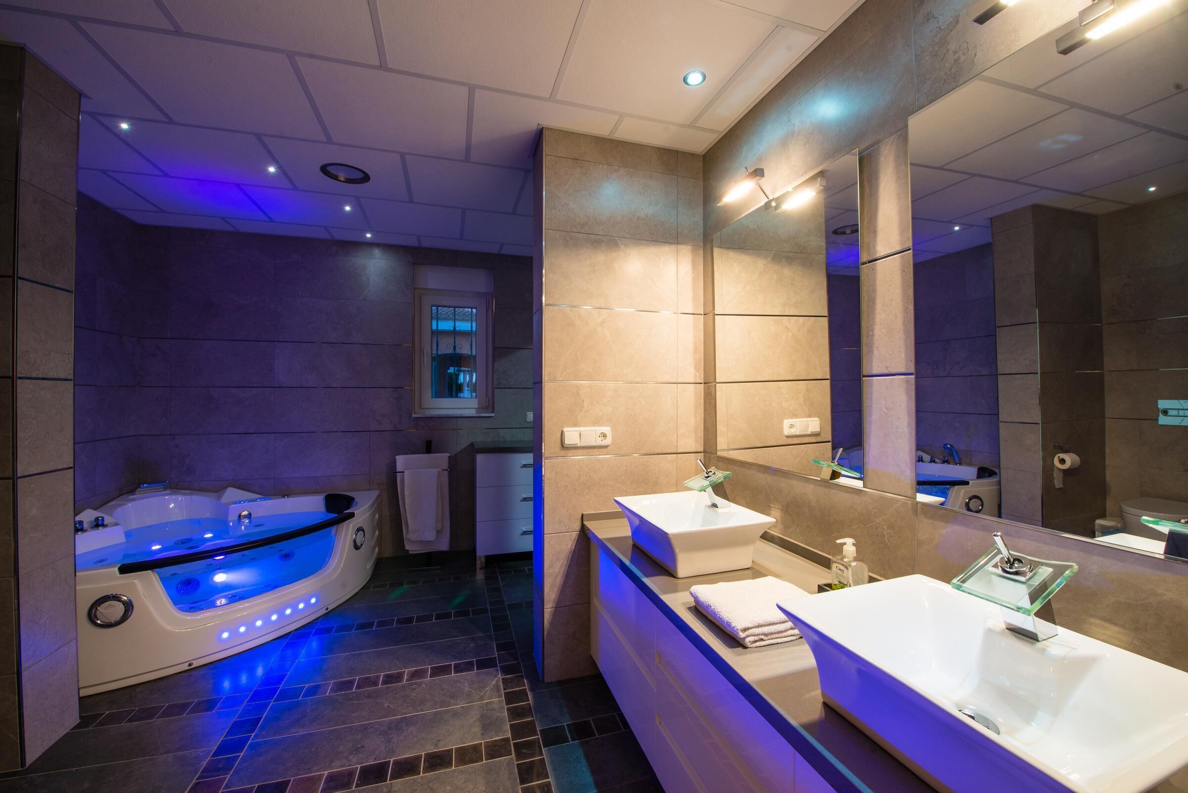 A modern bathroom with a large bathtub, two sinks, and a mirror.