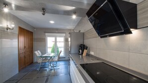 A modern kitchen with a built-in stove, wooden cabinets, and a glass dining table. - Modern villa with HEATED POOL & 400 m from the spa La Laguna hotel (Quesada, Alicante)