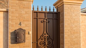A gated entrance with a decorative metal gate, brick walls, and a mailbox. - Modern villa with HEATED POOL & 400 m from the spa La Laguna hotel (Quesada, Alicante)