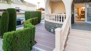 A wooden deck with a stone wall and a white balustrade leading to a covered patio area. - Modern villa with HEATED POOL & 400 m from the spa La Laguna hotel (Quesada, Alicante)
