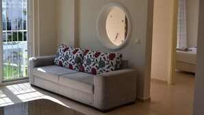 Una sala de estar con un sofá, un espejo redondo y vistas a un balcón.