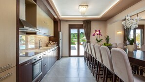 Una cucina moderna con zona pranzo, caratterizzata da una grande isola, mobili contenitori integrati e vista sull'esterno.