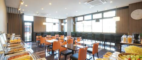 A buffet with various food options, tables, and chairs arranged in a spacious room with large windows.