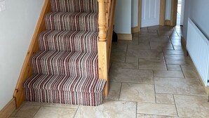 A staircase with striped carpet and wooden railings, leading to a door with a white frame. - Larchfield, at the centre of the unique North Antrim Coast (Bushmills)
