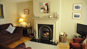 A living room with a fireplace, a sofa, a television, and artwork on the walls. - Larchfield, at the centre of the unique North Antrim Coast (Bushmills)