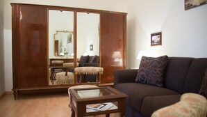 A living room with a dark brown sofa, a glass-top coffee table, a wooden cabinet, and a small side table.