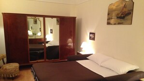 A bedroom with a bed, a wardrobe, a chair, and a painting on the wall.