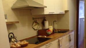 A kitchen with white cabinets, a wooden countertop, and a stainless steel sink.