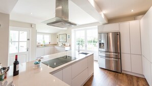 A modern kitchen with a central island, stainless steel appliances, and large windows.