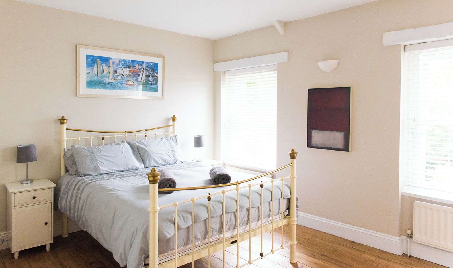 A bedroom with a bed, nightstand, and a painting on the wall.