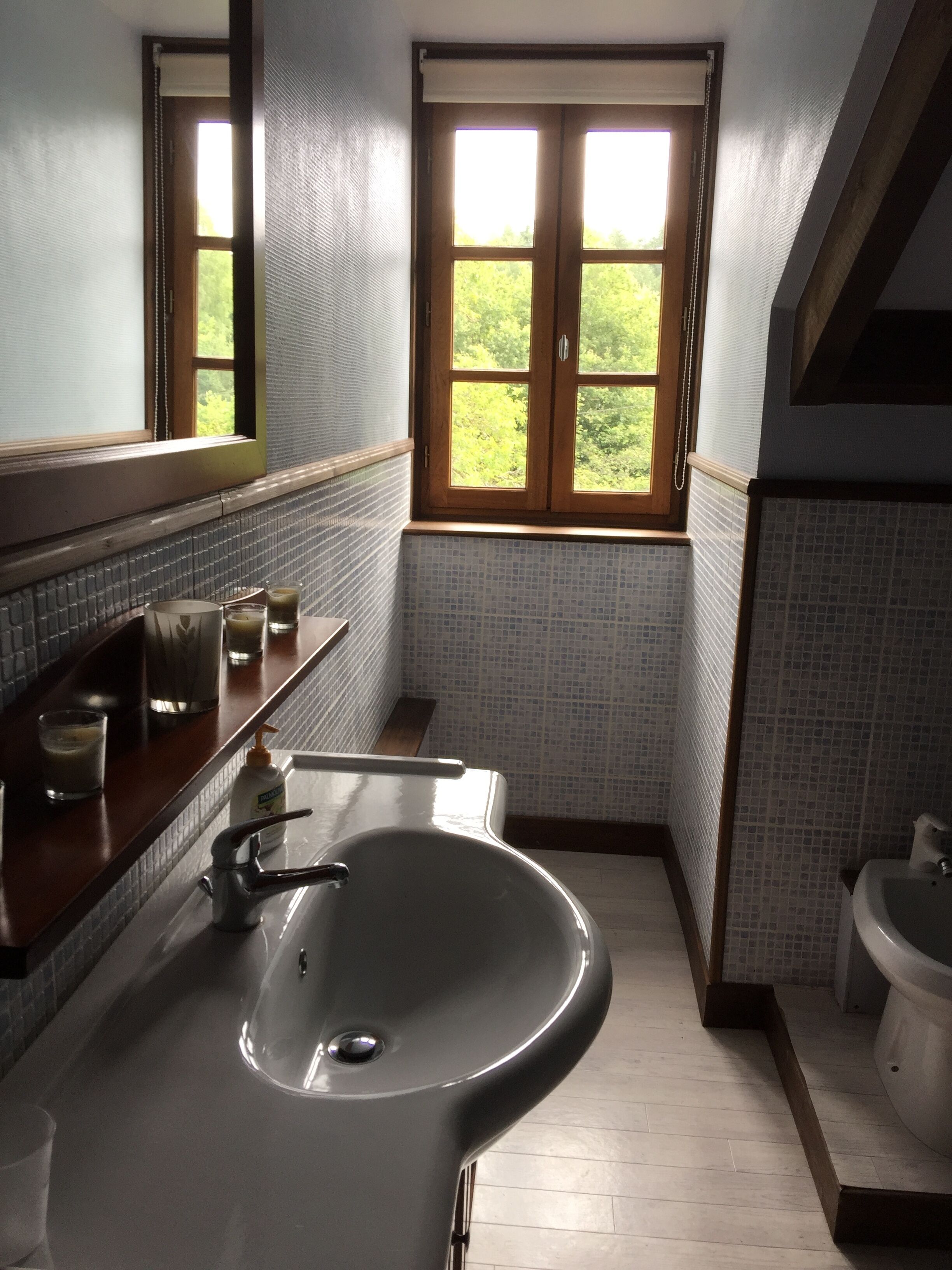 Une salle de bain dotée d’une grande baignoire, d’un lavabo et d’une fenêtre donnant sur un paysage verdoyant.